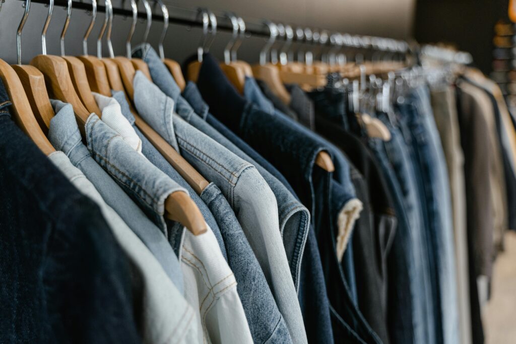 About Us A close-up view of various denim jackets hanging on a clothes rack indoors.